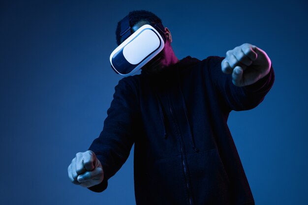 Young african-american man in VR-glasses in neon on blue