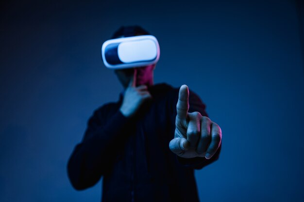 Young african-american man in VR-glasses in neon light on blue
