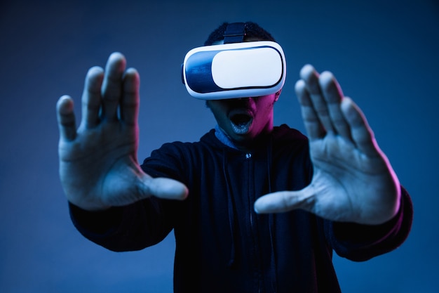 Young african-american man in VR-glasses in neon light on blue