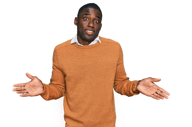 Young african american man wearing casual clothes clueless and confused expression with arms and hands raised doubt concept