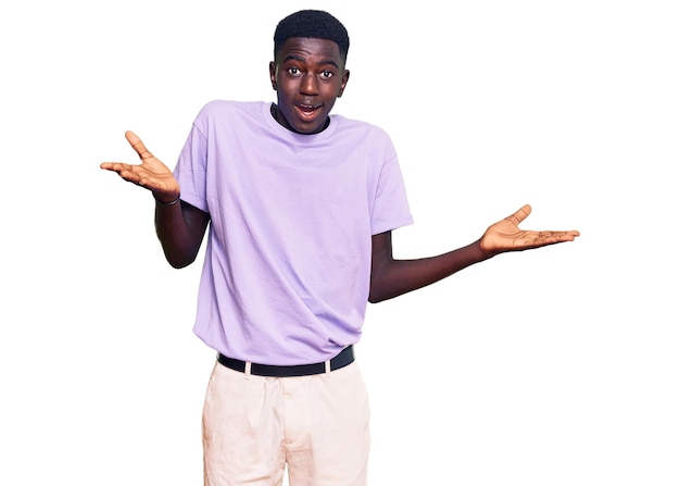 Young african american man wearing casual clothes clueless and confused expression with arms and hands raised doubt concept