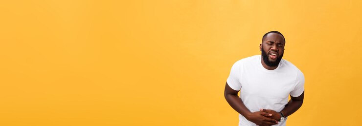 Free Photo young african american man wearing white tshirt with hand on stomach because nausea painful disease