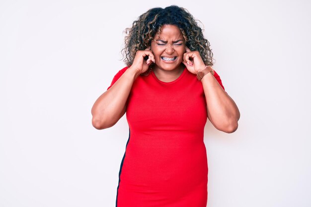 Young african american plus size woman wearing casual clothes covering ears with fingers with annoyed expression for the noise of loud music. deaf concept.