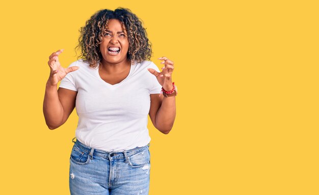 Young african american plus size woman wearing casual clothes crazy and mad shouting and yelling with aggressive expression and arms raised frustration concept