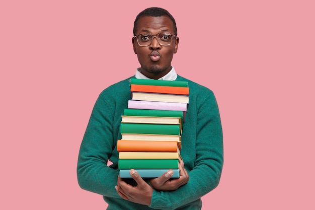 Бесплатное фото Молодой афро-американский студент, держащий кучу книг
