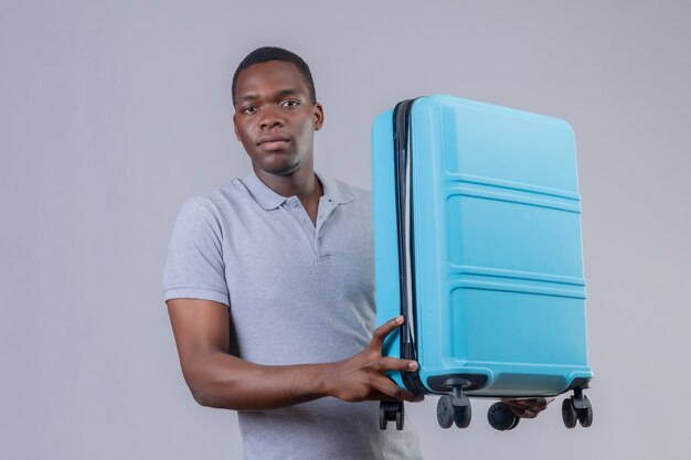 얼굴에 심각한 자신감 표정으로 파란색 가방을 들고 회색 폴로 셔츠에 젊은 아프리카 계 미국인 여행자 남자