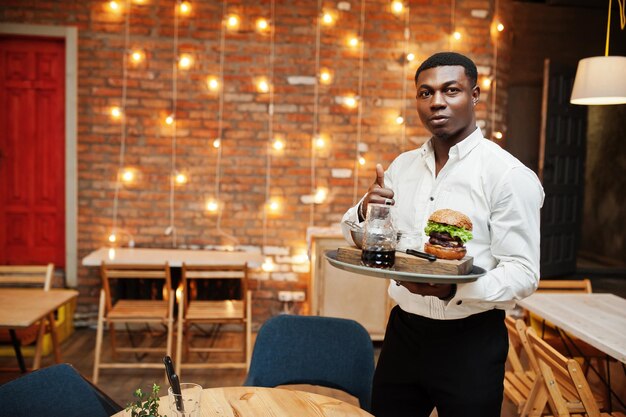 Young african american waiter man hold tray with burger at restaurant and show thumb up