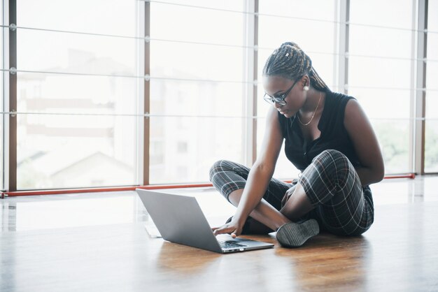 Молодая Афро-американская женщина счастлива с портативным компьютером.