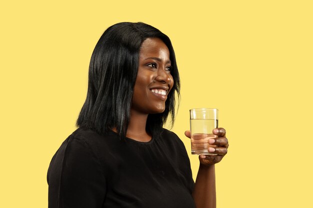 Young african-american woman isolated on yellow  space, facial expression. Beautiful female half-length portrait.