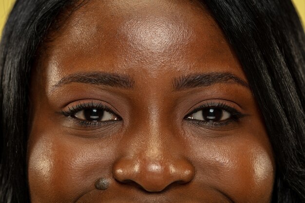 Молодая афро-американская женщина, изолированные на желтом пространстве, выражение лица. Красивые женские глаза крупным планом портрет
