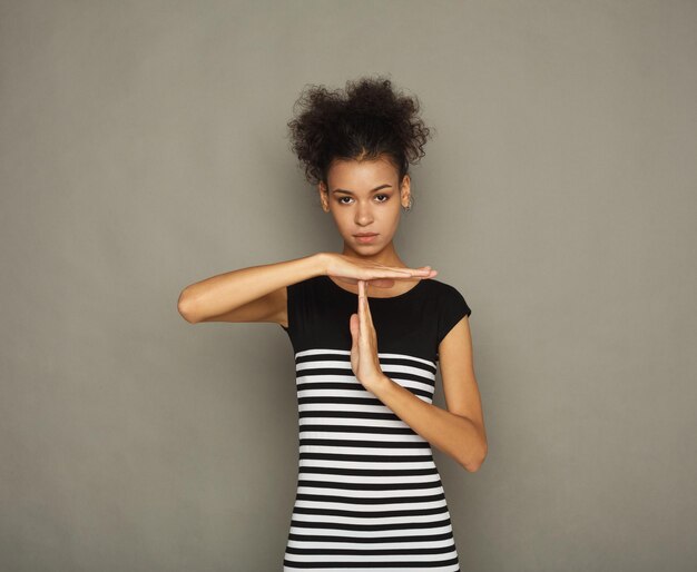 Young african-american woman making time out gesture, sign to ask for time, deadline concept, gray studio background