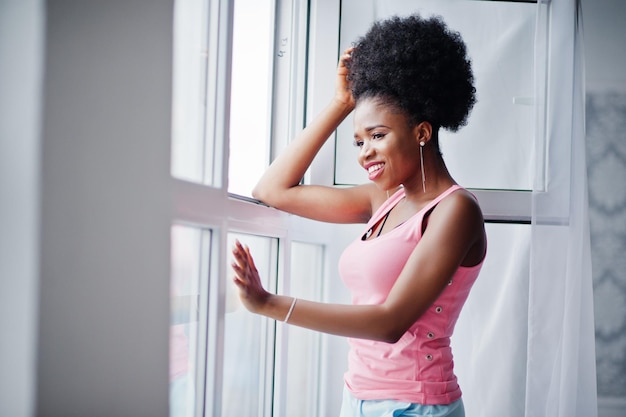 Молодая африканская американка в розовой майке у окна Идеальное утро
