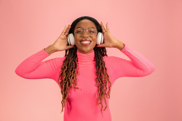 Young african-american woman's portrait isolated on pink background.