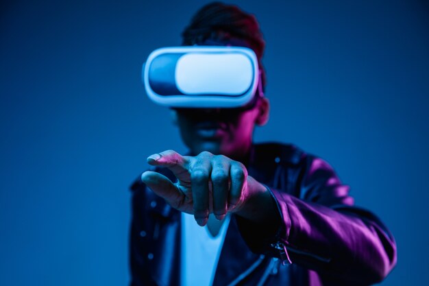 Young african-american woman's using VR-glasses in neon light