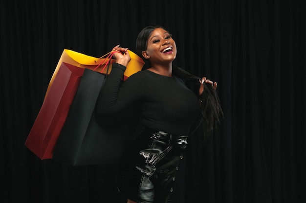 Free photo young african-american woman shopping with colorful packs on black