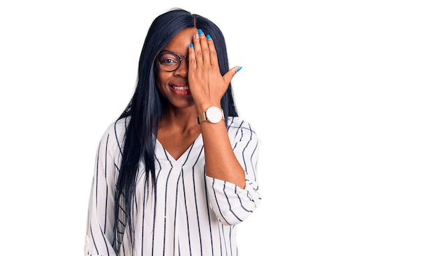 Free photo young african american woman wearing casual clothes and glasses covering one eye with hand confident smile on face and surprise emotion