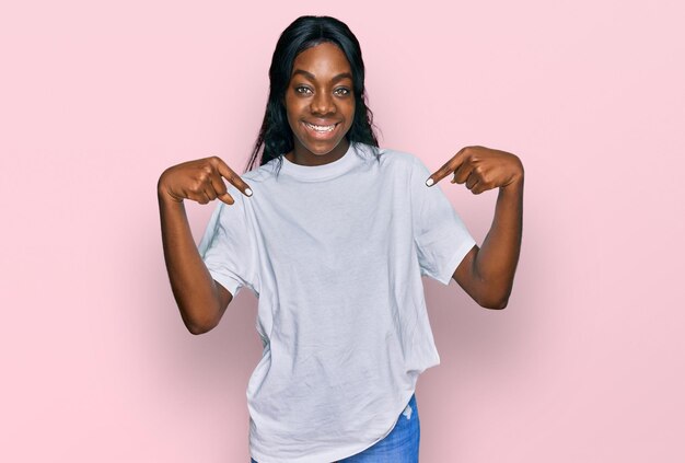 Free photo young african american woman wearing casual white t shirt looking confident with smile on face pointing oneself with fingers proud and happy