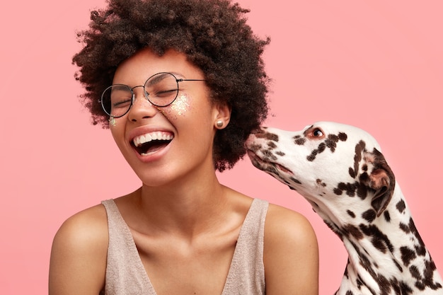 Молодая афро-американская женщина с блеском на лице и ее собака