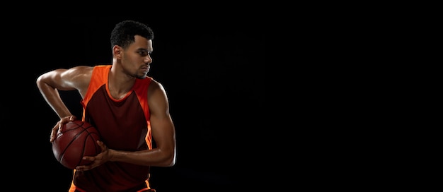 Young african basketball player training on black studio.