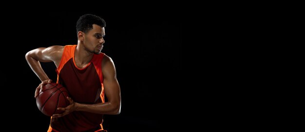 검은 스튜디오에서 훈련하는 젊은 아프리카 농구 선수.