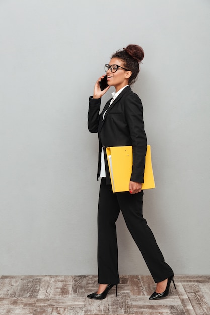 Young african business woman standing over grey wall