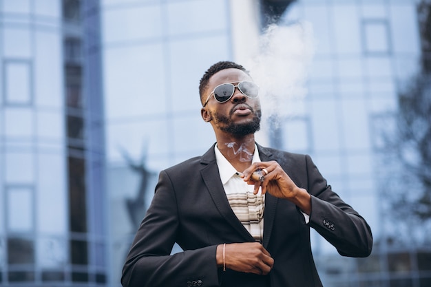 Young african businessman in classy suit smoking cigarette