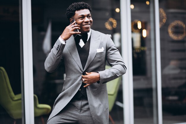 Молодой африканский бизнесмен используя телефон
