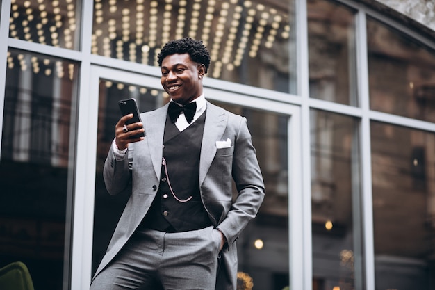 Молодой африканский бизнесмен используя телефон