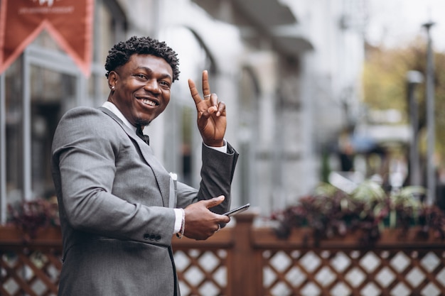 Foto gratuita giovane uomo d'affari africano che per mezzo del telefono