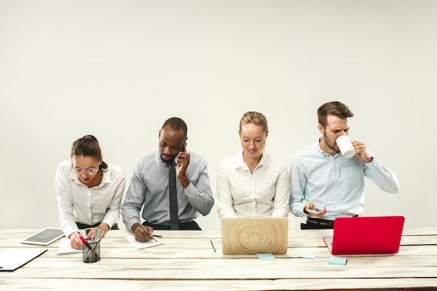 Free photo young african and caucasian men and women sitting at office and working on laptops. the business, emotions, team, teamwork, workplace, leadership, meeting concept. different emotions of colleagues