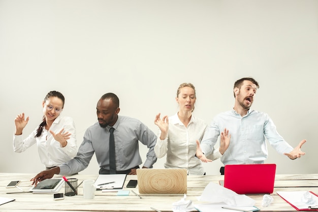 Giovani uomini e donne africani e caucasici seduti in ufficio e lavorando su laptop. il business, le emozioni, la squadra, il lavoro di squadra, il posto di lavoro, la leadership, il concetto di riunione. diverse emozioni dei colleghi