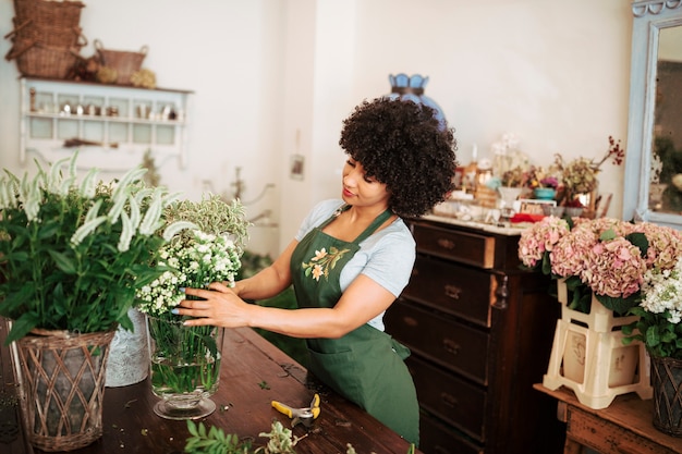 若いアフリカの女性の花屋が花を店に並べる