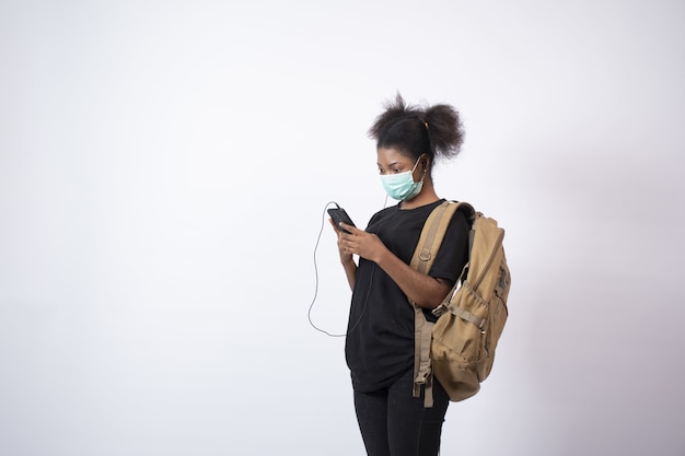 Free photo young african female wearing a face mask using her mobile phone