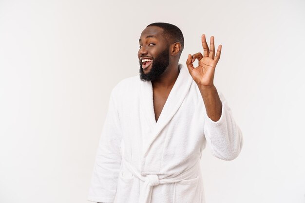 Young African man in bathrobe prepare for skin care showing ok finger sign Human emotions concept