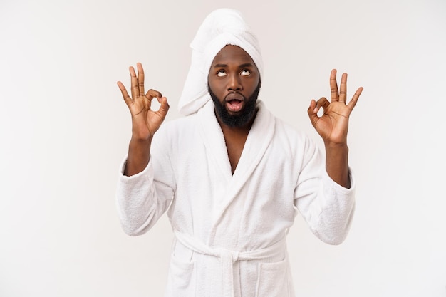 Young African man in bathrobe prepare for skin care showing ok finger sign Human emotions concept