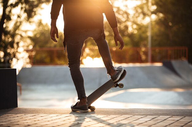 Молодой африканский человек делает скейтбординг на открытом воздухе