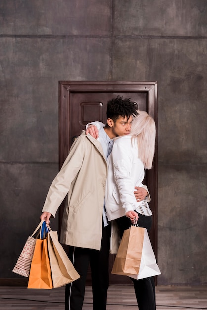 Young african man hugging her girlfriend holding many shopping bags in hand