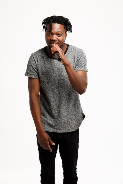 Young african man singing in microphone on white.