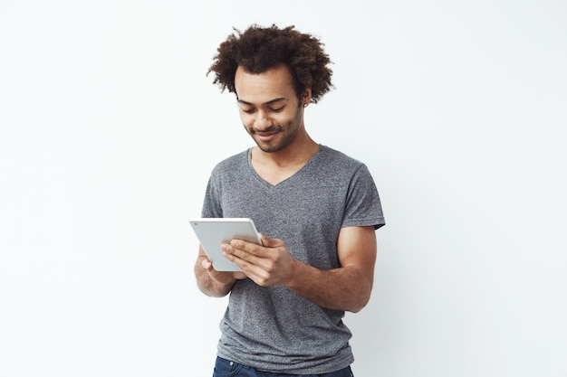 Young african man smiling looking at tablet.