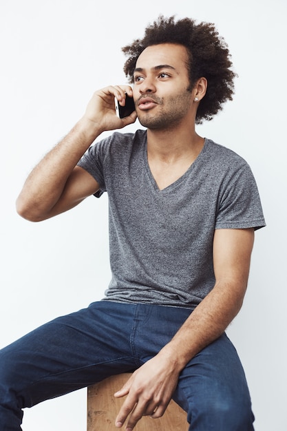 전화 앉아 얘기하는 젊은 아프리카 남자.