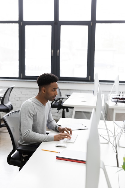 Free photo young african office worker sitting at a desk