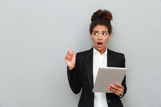 Young african shocked business woman over grey wall