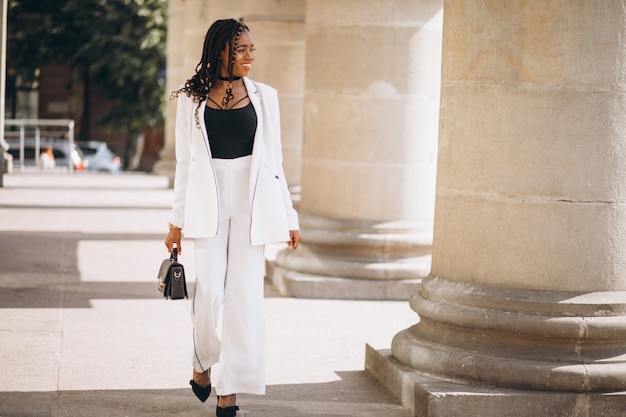 Foto gratuita la giovane donna africana si è vestita in vestito bianco fuori della strada