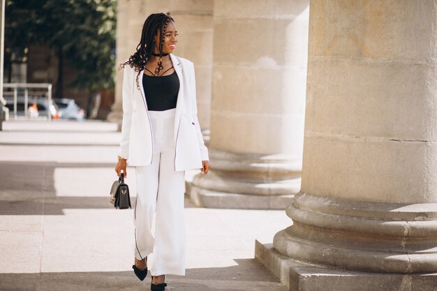 Young african woman dressed in white suit outside the street