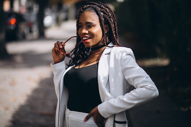 Young african woman dressed in white suit outside the street