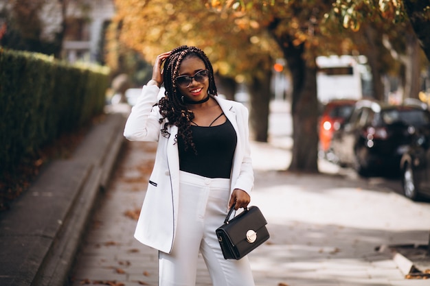 Young african woman dressed in white suit outside the street