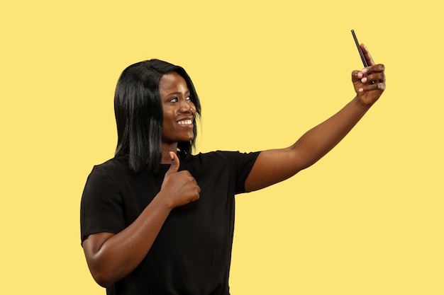 Young african woman isolated on yellow studio background, facial expression