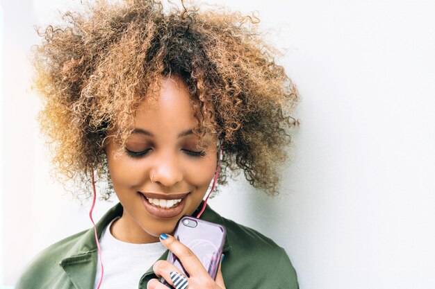 Young african woman listening to music outside on city street