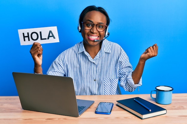 Free photo young african woman wearing operator headset holding hola word screaming proud, celebrating victory and success very excited with raised arm