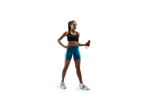 Young african woman with water before run isolated on white studio background. One female runner or jogger. Silhouette of athlete.